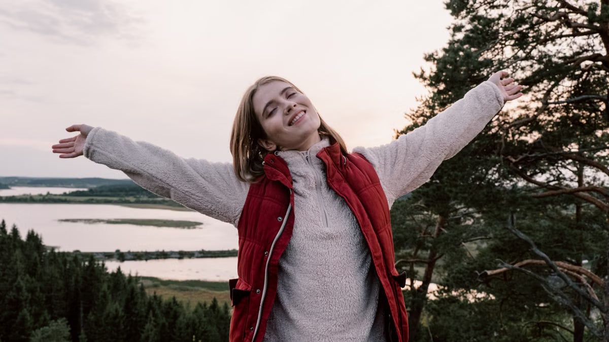 Woman enjoying freedom in a scenic landscape with open arms.
